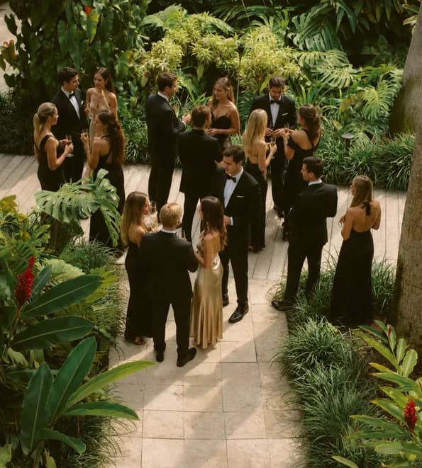 Founders in black tie mingling with drinks along a garden path